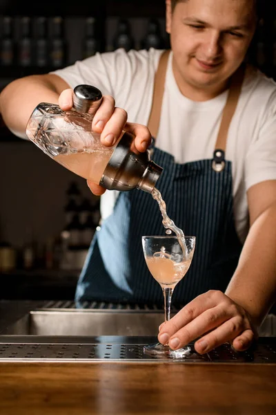 Camarero sostiene agitador y vierte cóctel frío en el vaso en el mostrador de bar —  Fotos de Stock