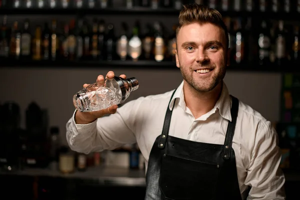 Attraktiv ung leende man bartender håller ett glas shaker i handen — Stockfoto