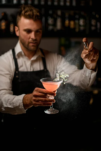 Bicchiere da cocktail con bevande alcoliche barista tiene in mano e spruzza su di esso — Foto Stock