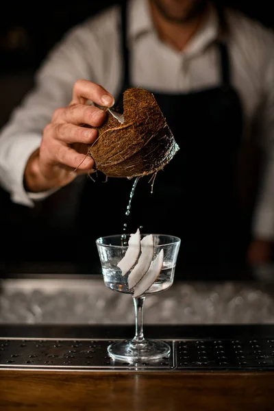 Pedaço de coco em uma mão masculina sobre copo de coquetel com bebida — Fotografia de Stock