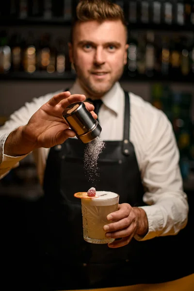 Mano de barman sostiene vidrio con cóctel espumoso y espolvorear con polvo —  Fotos de Stock