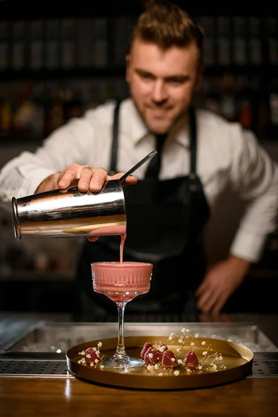 Mano de camarero vierte cóctel de coctelera en soportes de cristal en bandeja redonda —  Fotos de Stock