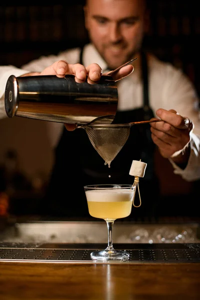 Hände des Barkeepers seihen den Cocktail sanft durch ein Sieb in ein Glas — Stockfoto