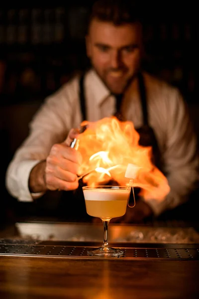 Barista spruzza su vetro con cocktail sul bancone del bar e fa fuoco su di esso. — Foto Stock