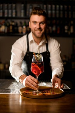 Erkek barmenin eli nazikçe yüksek şarap bardağını alkollü kokteyl ile tutuyor.