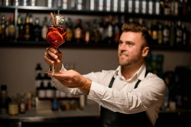 Gülümseyen barmen elinde alkollü kokteyl kadehi tutuyor.
