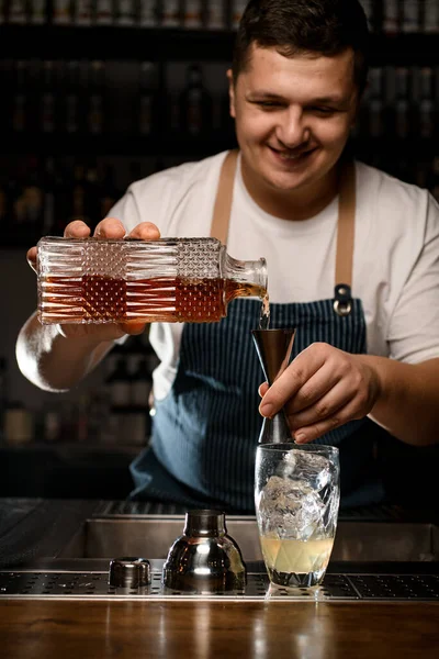 Barman masculino derrama líquido de garrafa em jigger de aço. — Fotografia de Stock