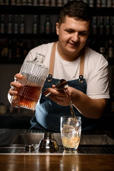 Ung bartender häller vätska från jigger i kristallblandningsbägare — Stockfoto