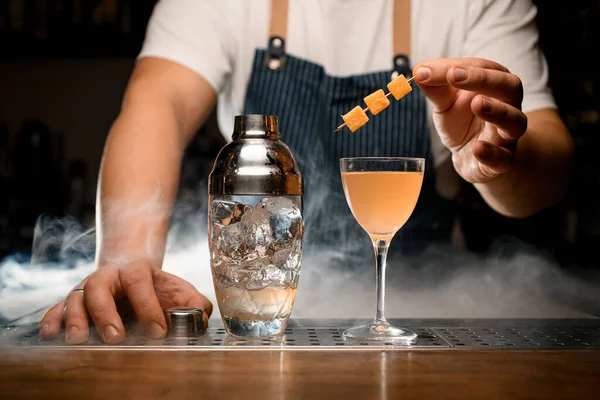 Bicchiere di cocktail freddo all'arancia e shaker trasparente con ghiaccio sul bancone del bar — Foto Stock