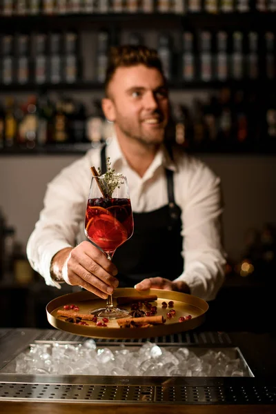 Mãos de barman masculino suavemente mantém salver com copo de vinho alto com coquetel alcoólico — Fotografia de Stock