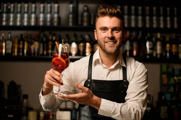 Hand manliga bartendern håller försiktigt Martini glas med cocktail. suddig kropp ung bartender i bakgrunden — Stockfoto