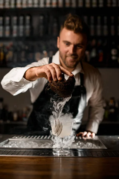 Barman profesional cuidadosamente verter bebida y humo de coco en vidrio —  Fotos de Stock