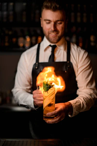 Camarero prende fuego a la bebida alcohólica transparente con pepino, menta y hielo — Foto de Stock