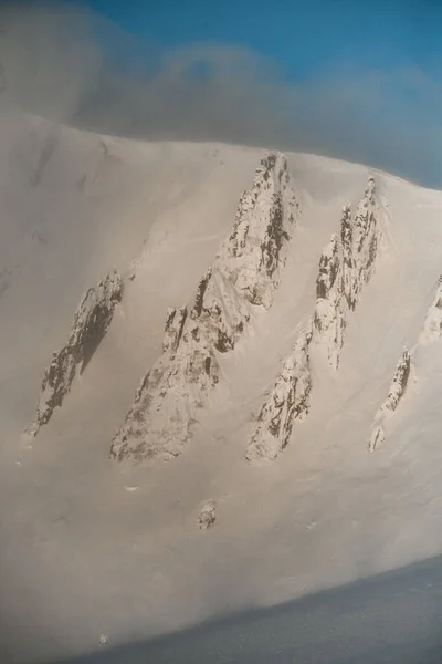 Vista aérea em bordas de pedra de uma montanha coberta de neve em pó branco. — Fotografia de Stock