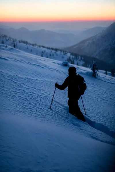 Esquiador com equipamento de caminhadas andando na encosta da montanha nevada. — Fotografia de Stock