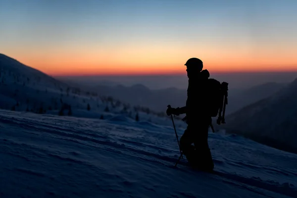 Силуэт туриста на снежной горе на фоне неба и заката — стоковое фото