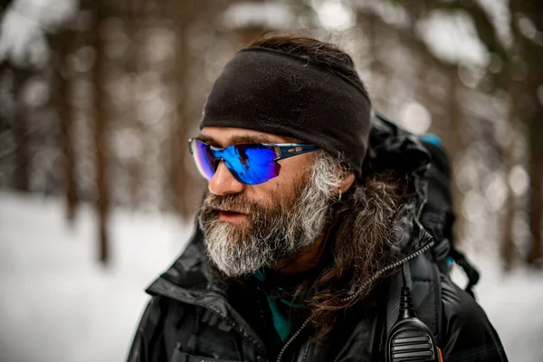 ชายในแว่นตากันแดดกับเคราสีเทาในแจ็คเก็ตฤดูหนาว — ภาพถ่ายสต็อก