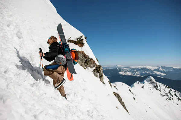 Man ski-climber with backpack and ski equipment climbing at snowy ridge — Fotografia de Stock