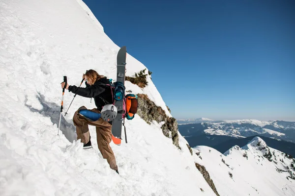 Man with backpack and ski equipment climbing at snowy ridge — Fotografia de Stock