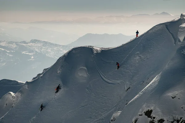 Прекрасный вид на склон горы, покрытый снегом, по которому поднимаются группы лыжников — стоковое фото