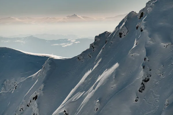 Beautiful snow-capped mountain slope at foreground and wonderful winter mountain landscape at background — Fotografia de Stock