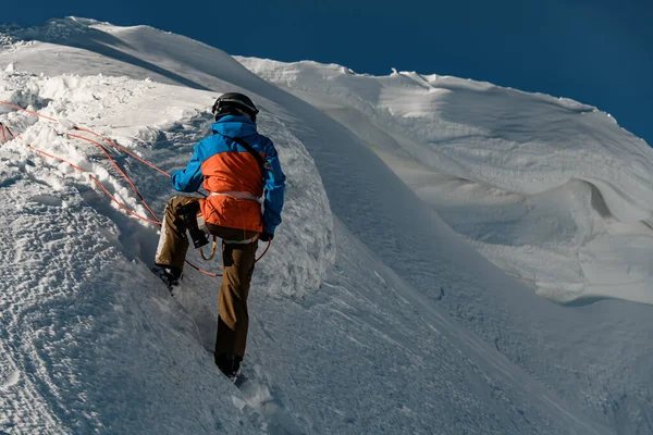 Vista trasera del hombre en traje de esquí sosteniendo la cuerda en la pendiente de la montaña — Foto de Stock