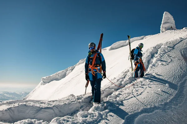 Группа лыжников в ярких лыжных костюмах с рюкзаками и лыжным снаряжением на снежном хребте. — стоковое фото