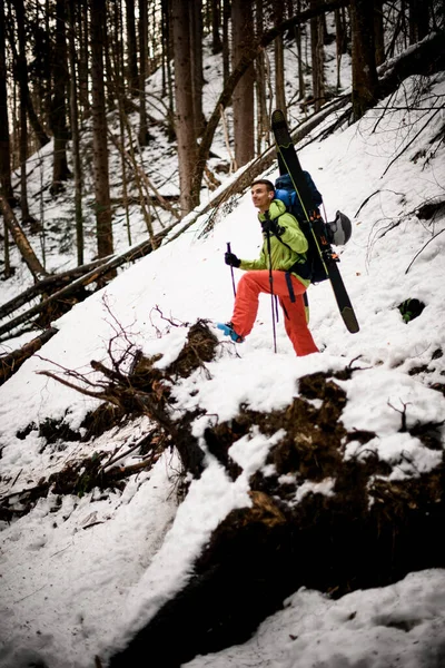 冬天，带着滑雪器材的年轻男性徒步旅行者站在森林里的一个陷阱上 — 图库照片