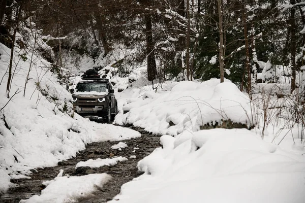 Gyönyörű kilátás a sziklás út egy hófödte téli erdő és off-road jármű — Stock Fotó