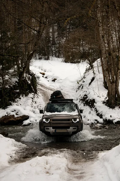 Beautiful view of the off-road car driving through the river in the winter snowy forest — Stock Photo, Image