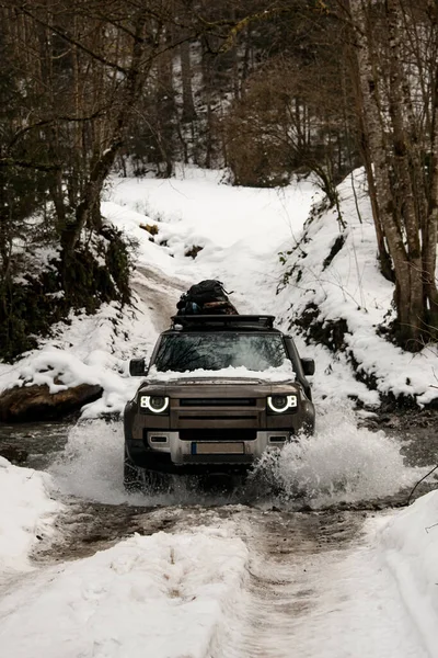 Nagyszerű kilátás nyílik a off-road autó áthajt a folyón a téli havas erdőben — Stock Fotó