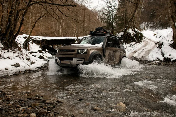 Off-road vehicle successfully rides across a mountain river at winter — Stock Photo, Image