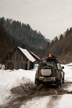 Dağlardaki karlı yolda off-road yolculuğunun arka görüntüsü. Dağ turizmi taşımacılığı.