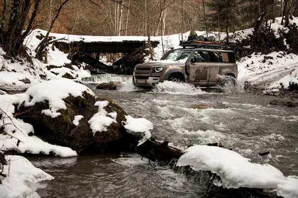 Off-road vehicle ride across a mountain river at winter — Stockfoto
