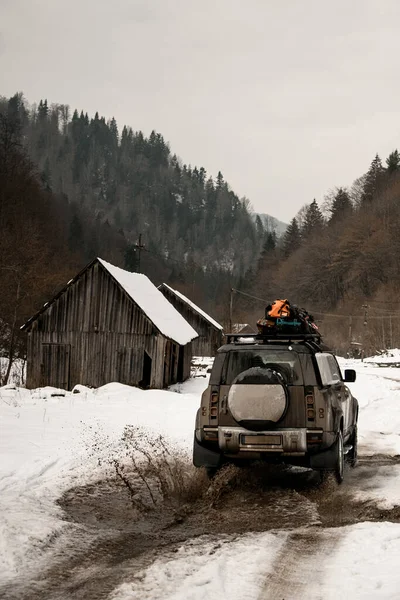 Rear view of off-road car ride on snowy road at mountains. Mountain tourism transport. — Stock Photo, Image