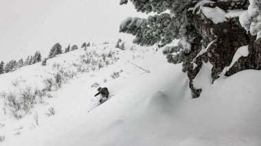 Karla kaplı güzel bir dağ yamacı ve hızla aşağıya inen bir kayakçı.