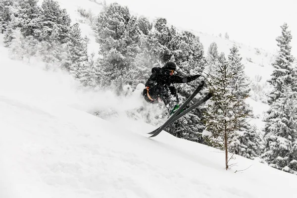 Profesjonalny narciarz skacze po pokrytym śniegiem zboczu góry — Zdjęcie stockowe