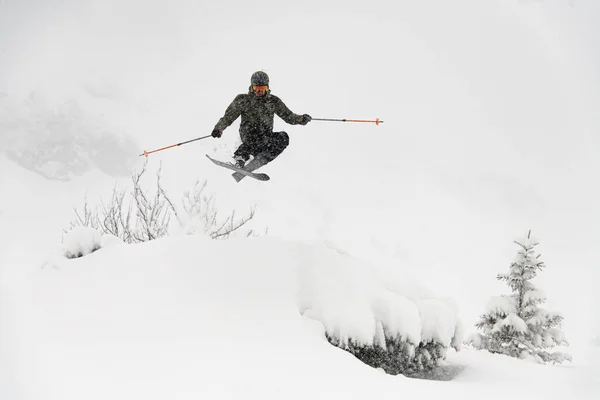 Shot of skier masterfully jumping in the air over a snow-covered mountain slope. Freeride skiing concept — Fotografia de Stock