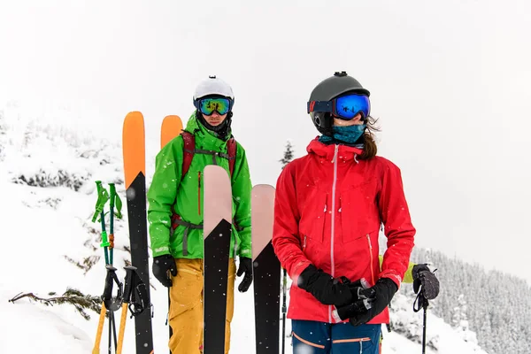 Kış dağ manzarası arka planında kayak ekipmanlarıyla iki kayakçının yakın çekimi