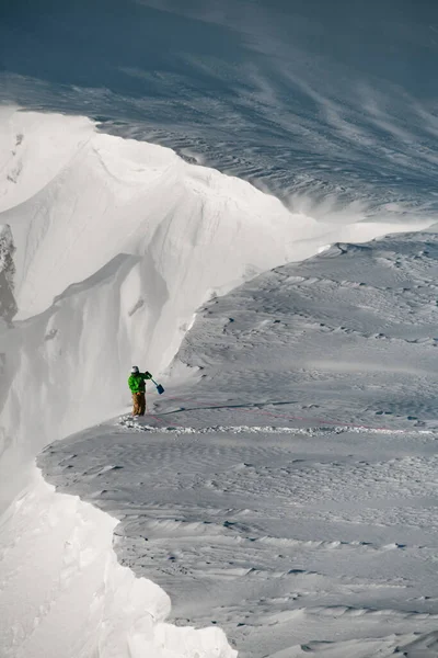 Karla kaplı dağ uçurumundaki hava manzarası ve kenarındaki ekipmanla dağcı. — Stok fotoğraf