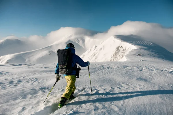 Achteraanzicht van de skiër met wandeluitrusting wandelen bij diepe sneeuw op de berghelling. — Stockfoto