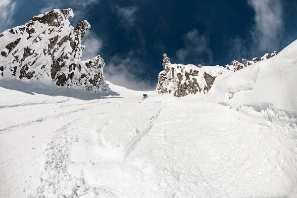 Wspaniały widok na ośnieżone zbocze górskie, wzdłuż którego biegnie narciarz — Zdjęcie stockowe