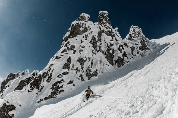 Freeride skier riding down on steep snowy mountain on a sunny day. — Stock Photo, Image