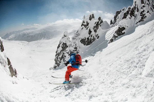 Active freeride skier energetically rides down on snow-covered mountain slope. — стоковое фото