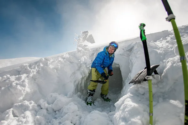 Человек в куртке в очках и лыжном шлеме держит лопату и рассеивает снег — стоковое фото