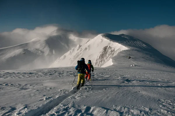 Group of skiers walking at snow trail on snow-covered mountain range — стоковое фото