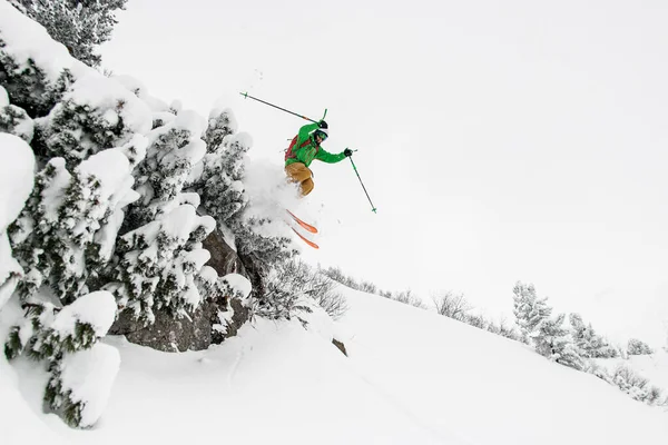 Male skier making jump while sliding down snow-covered slope on skis — Stock Photo, Image