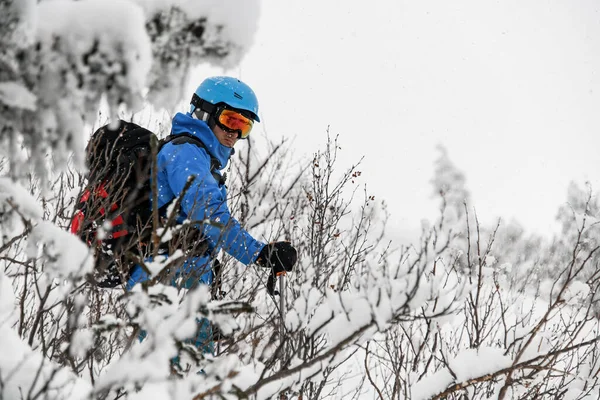 青いジャケットとスキーヘルメットとゴーグルを身に着けているバックパック付きの男のスキーヤー — ストック写真