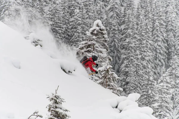 Skidåkare rider snabbt på snöig bergssluttning och stänk snö runt honom — Stockfoto