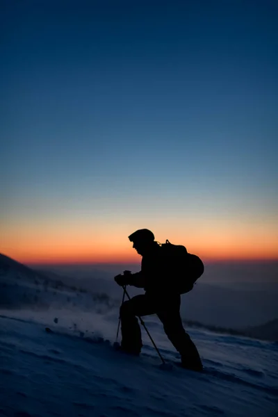 空と日の出を背景に雪に覆われた山頂のスキーヤーは — ストック写真